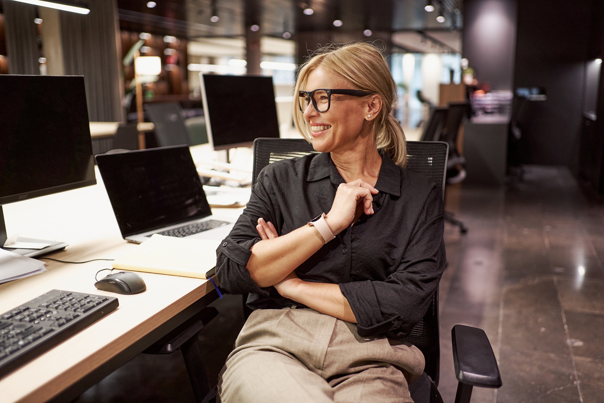 a woman sitting at a desk with her arms crossed