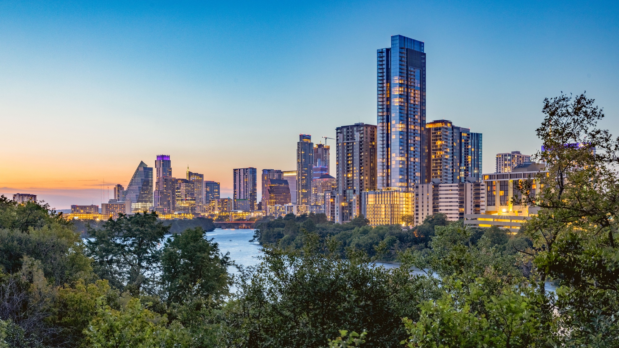 a city skyline with trees and water